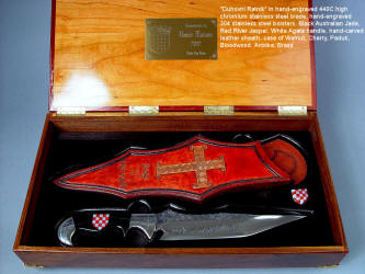 "Duhovni Ratnik" obverse side view. Knife in hand-engraved 440C high chromium stainless steel blade, hand-engraved 304 stainless steel bolsters, handle of Black Nephrite Jade gemstone inlaid with a mosaic of Red River Jasper and White Geodic Quartz. Sheath is hand-carved, hand-dyed leather shoulder