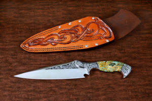 "Malaka" fine custom handmade knife, obverse side view  in hand-engraved CPM 154CM powder metal technology stainless steel, T4 deep cryogenically treated, bolsters of hand-engraved 304 stainless steel, Plasma agate and Nephrite Jade gemstone handle, hand-carved leather crossdraw sheath with stainless steel hardware