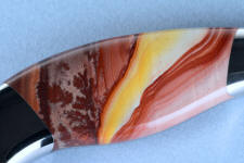 This Hickoryite Rhyolite gemstone knife handle shows bright yellows, oranges, reds and pinks with some dendtiric forms and flowing bands. It's extremely durable and hard, taking a bright glassy polish